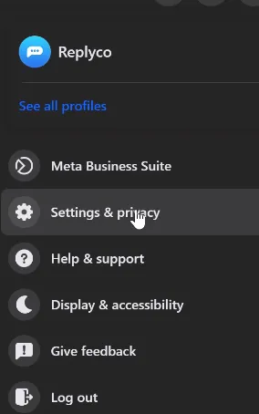 Facebook's profile menu in dark mode while you act as the business page. The page's profile is at the top with "See all profiles" below it. The menu then lists "Meta Business Suite", "Settings & privacy", with the pointer on it, "Help & support", "Display & accessibility", "Give feedback" and "Log out". Select Settings & privacy to reach the page's settings.
