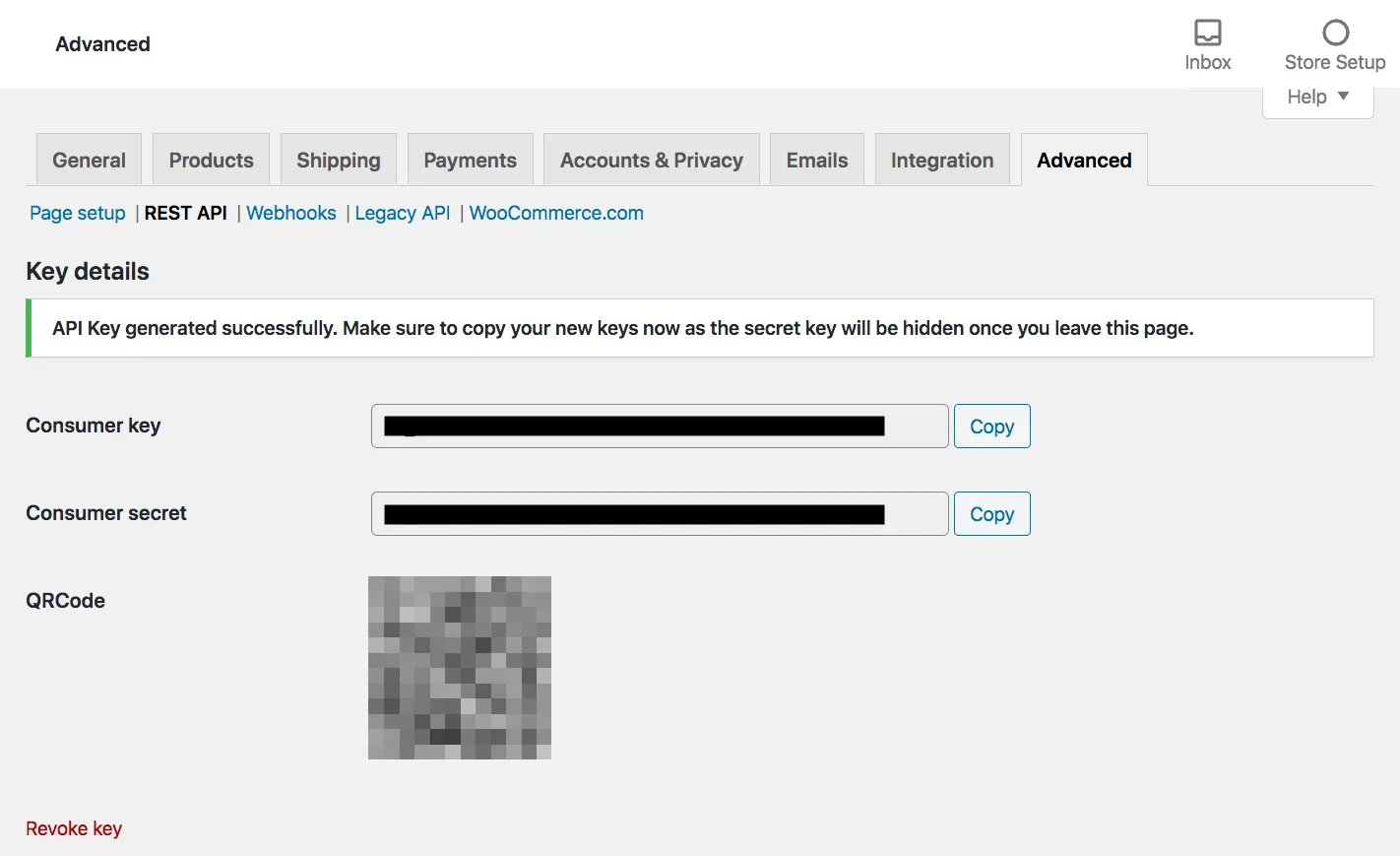 The WooCommerce settings at the Advanced tab, with the tabs General, Products, Shipping, Payments, Accounts & Privacy, Emails, Integration and Advanced, and the REST API section selected. A green notice reads "API Key generated successfully. Make sure to copy your new keys now as the secret key will be hidden once you leave this page." Below it, Consumer key and Consumer secret each have a Copy button; their values are blacked out. A QR code, blurred because it holds the same keys, and a Revoke key link follow.